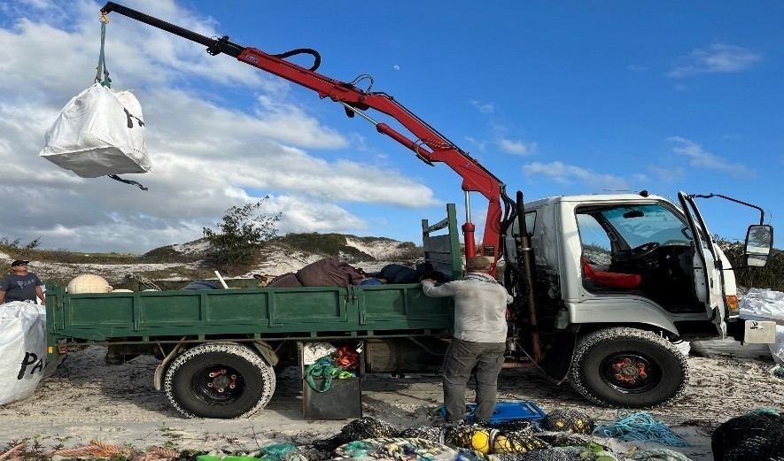 A crane truck lifting a bulk bag of recovered nets